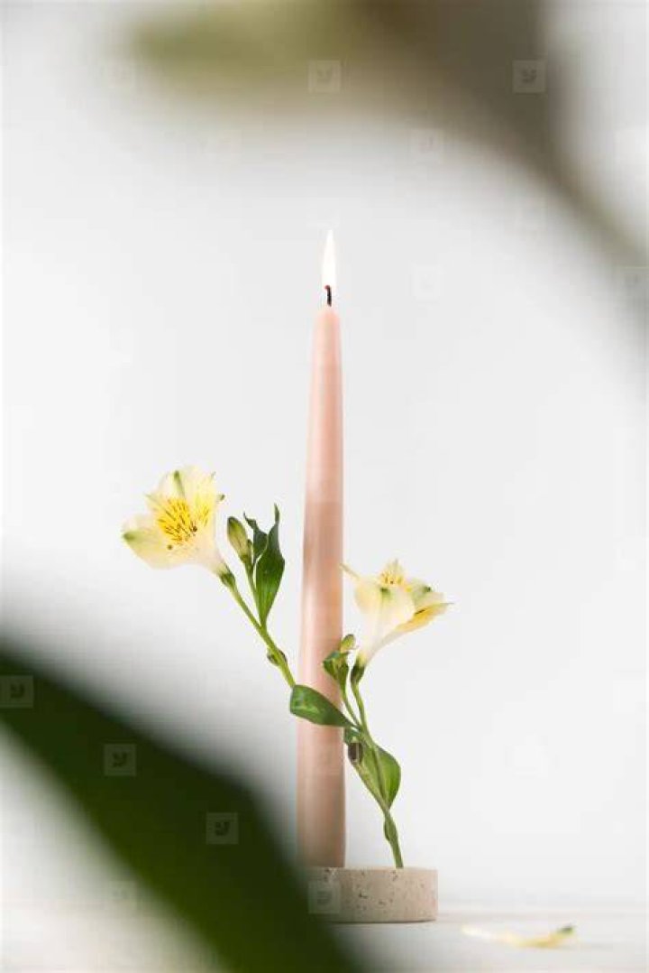 Pink candle burning with a flame at its center of pooling wax during a ritual